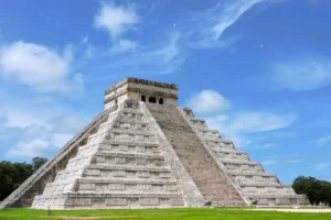 Front view of the El Castillo Mayan pyramid at Chichen Itza under a blue cloudy sky