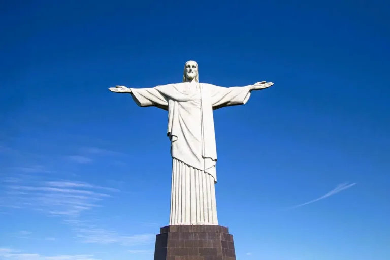 The Christ the Redeemer statue standing tall with open arms against a bright blue sky