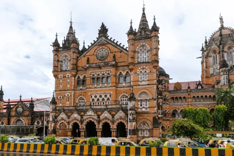 Ornate Victorian Gothic architecture of the Chhatrapati Shivaji Maharaj Terminus in Mumbai with yellow taxis