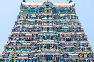 Close-up view of the brightly painted, multi-tiered gopuram tower covered in detailed sculptures at Meenakshi Amman Temple