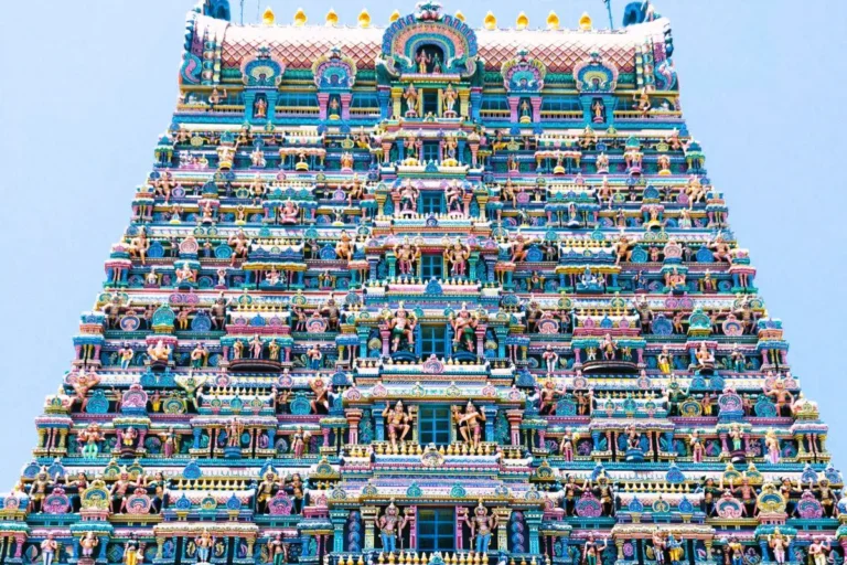 Close-up view of the brightly painted, multi-tiered gopuram tower covered in detailed sculptures at Meenakshi Amman Temple