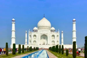 The iconic white marble facade and central dome of the Taj Mahal viewed across the reflecting pool and symmetrical gardens
