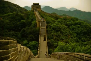 Stone walkway and watchtowers of the Great Wall of China winding across lush green mountains