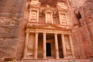 Intricately carved stone facade of The Treasury (Al-Khazneh) nestled within the pink sandstone cliffs of Ancient Petra
