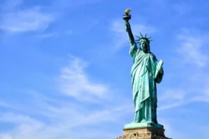 Statue of Liberty on Liberty Island in New York Harbor, viewed from below against a bright blue sky